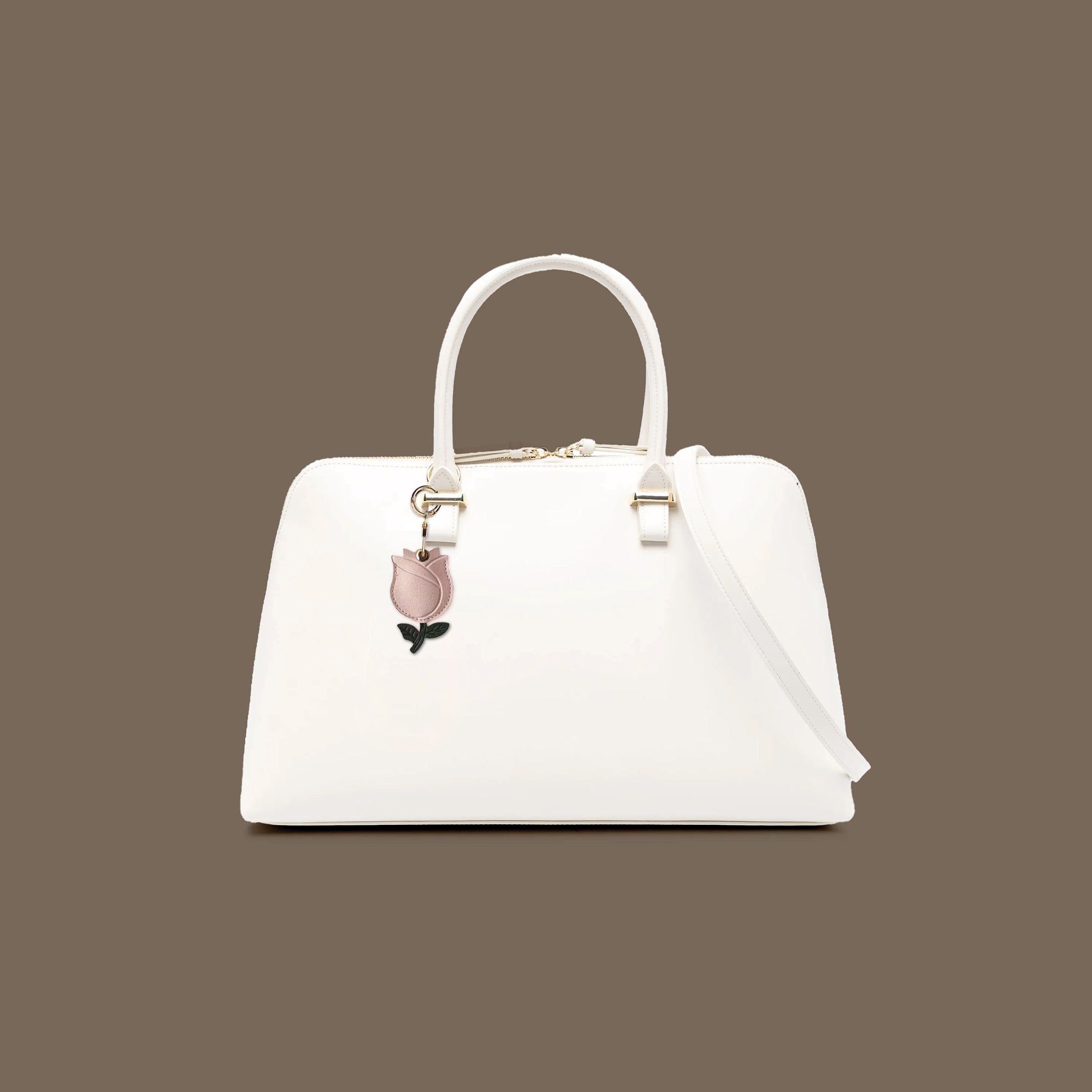 Tulip leather AirTag holder attached to white handbag with gold key ring accessory