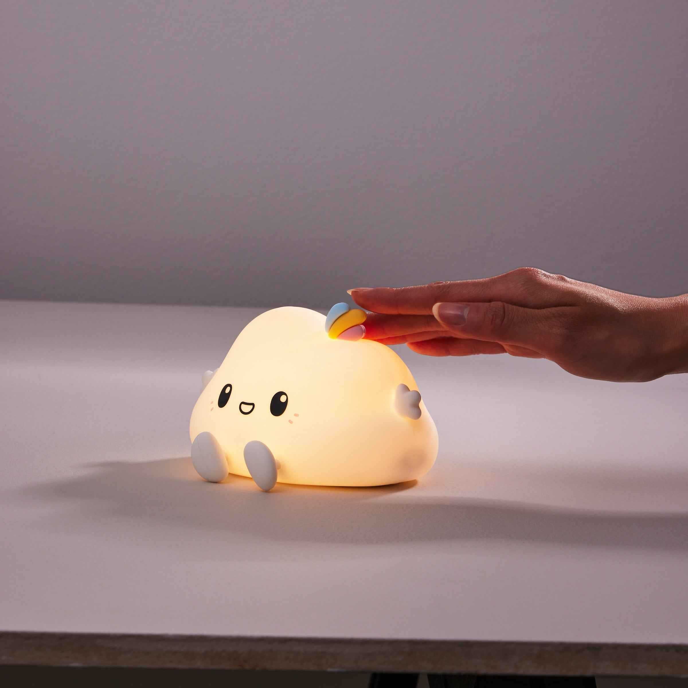 Cute cloud-shaped night light with touch control and warm ambient glow shown being activated by hand