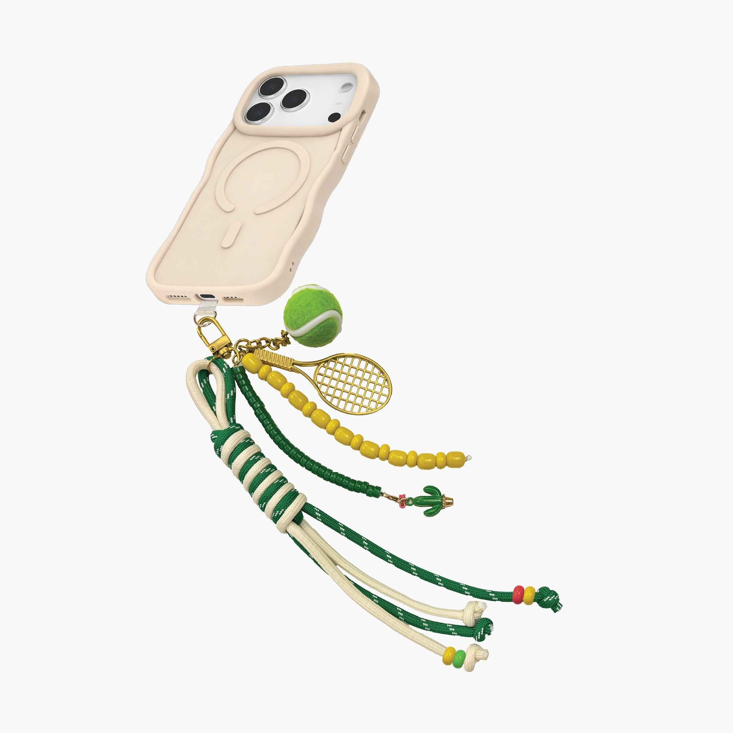 Tennis-themed wristlet phone strap attached to MagSafe phone case with tennis ball charm, racket pendant, and adjustable rope design