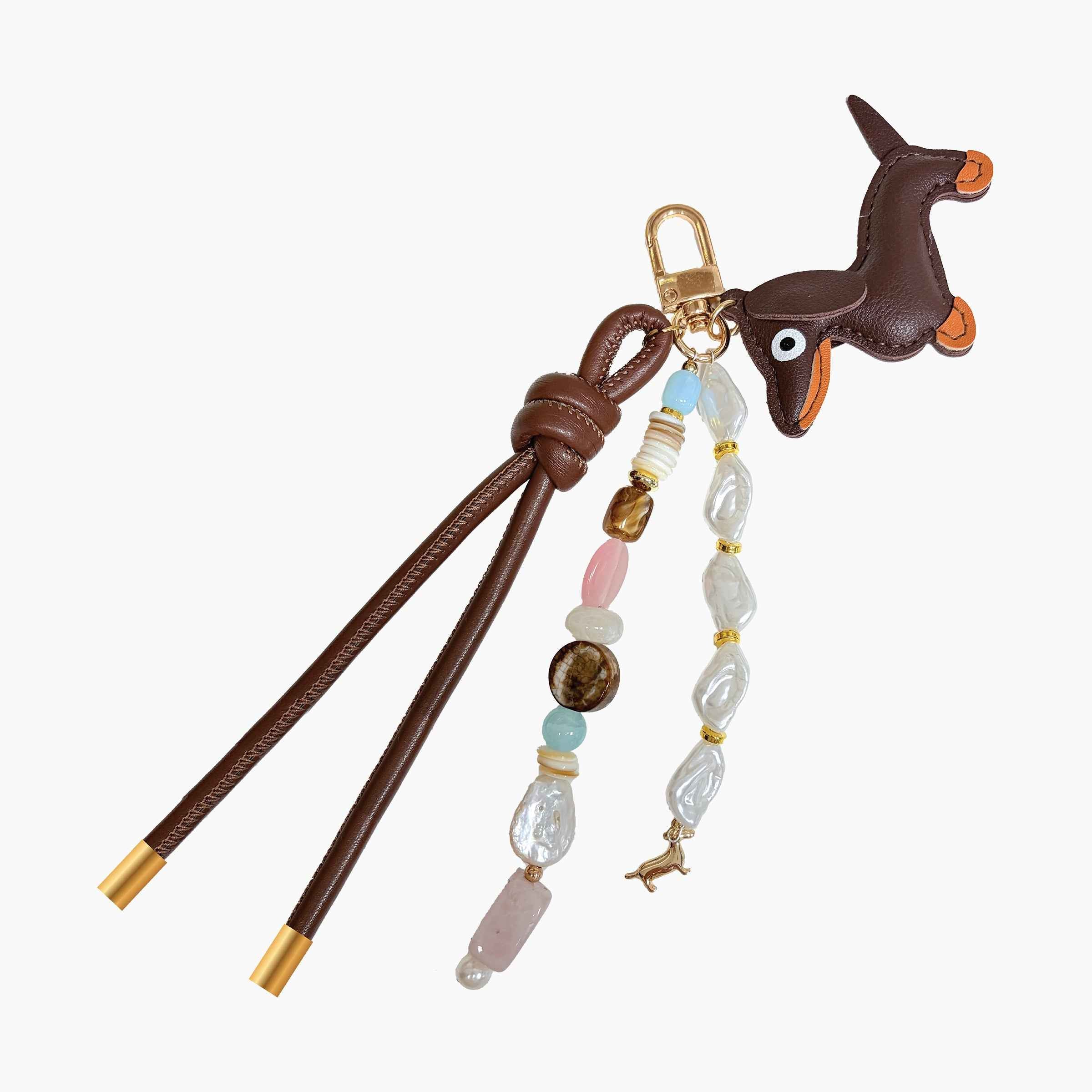 Dachshund-inspired bag charm featuring leather dog pendant, gemstone-style beads, pearl accents, decorative tassels, and gold-tone hardware