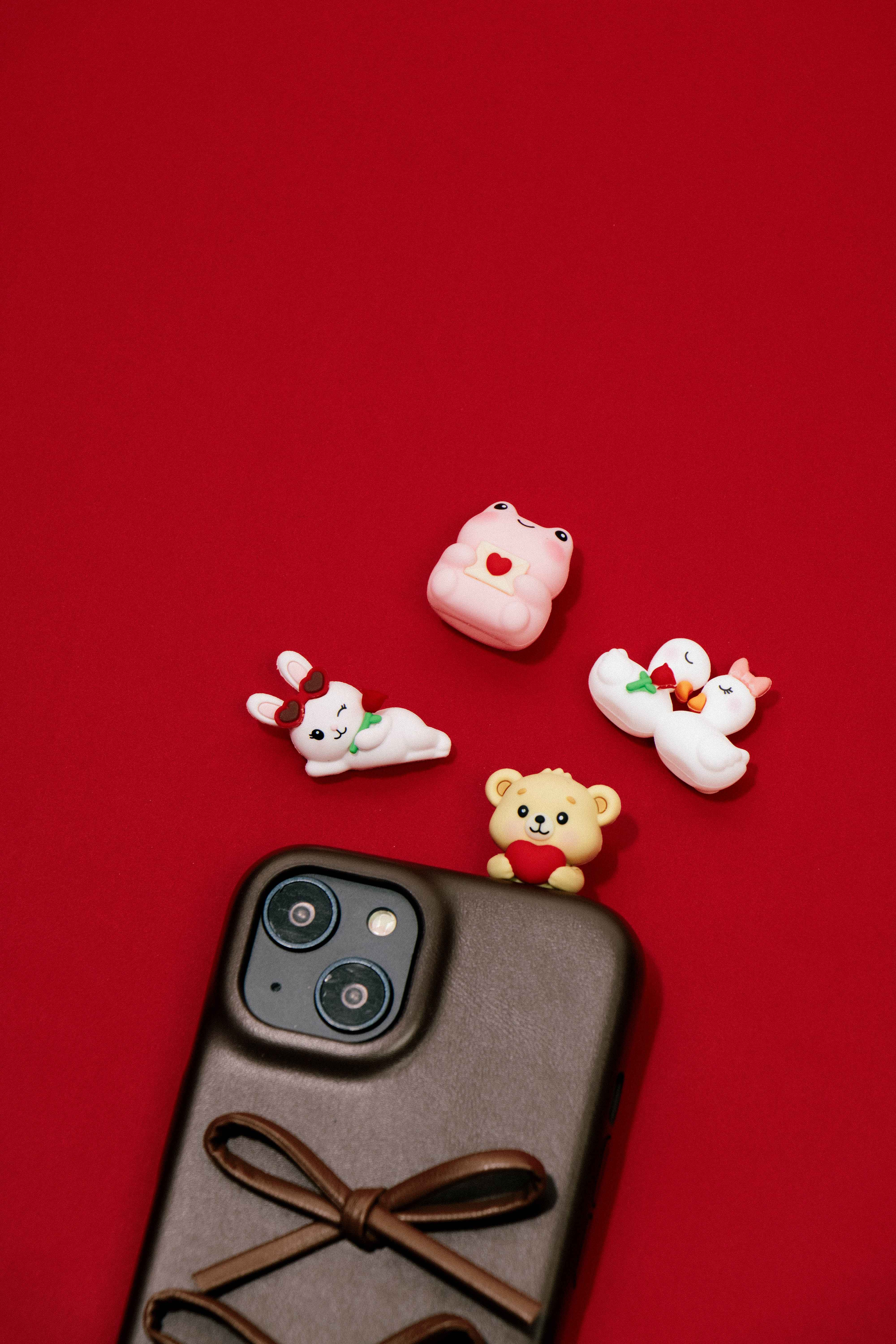 Peek-A-Pals Love Notes collectible figure collection featuring bunny, frog, swan, and teddy bear companions displayed with a smartphone as cute phone decorations and desk accessories