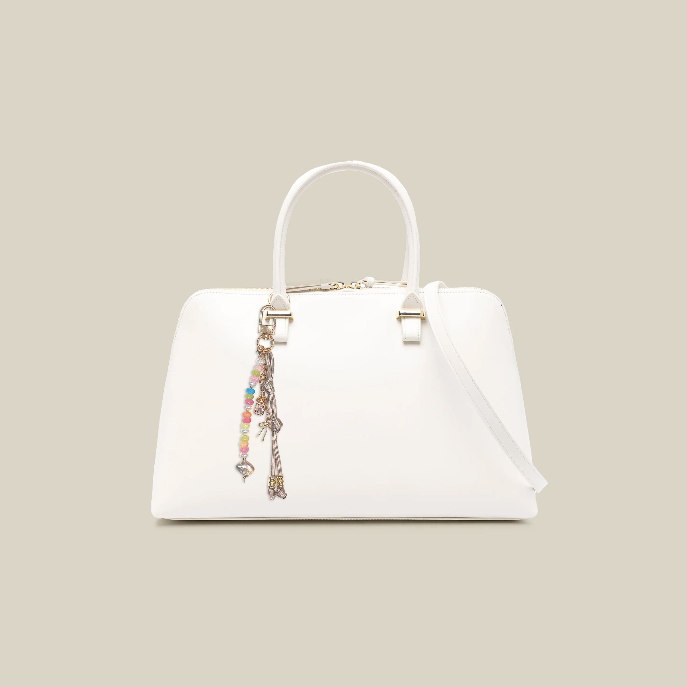 Colorful beaded bag charm attached to a white handbag featuring pastel gemstone-style beads, braided cord details, and decorative gold-tone accents