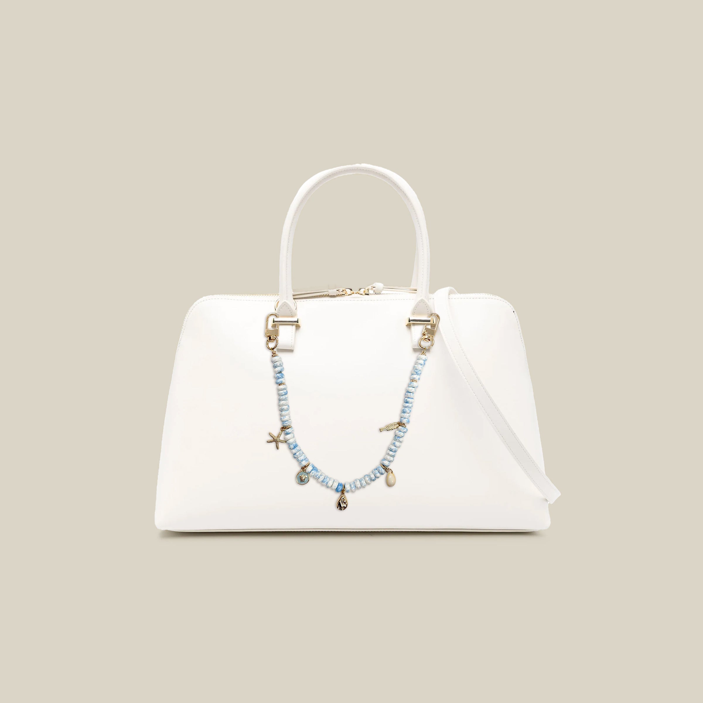 Ocean-inspired beaded bag charm attached to white handbag featuring blue gemstone-style beads, seashell charms, starfish accent, and coastal-inspired details
