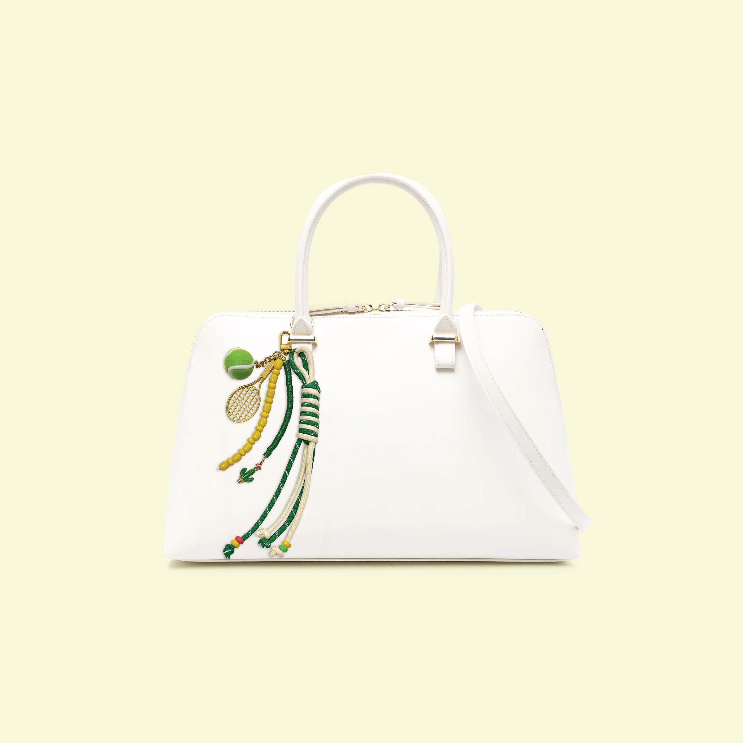 Tennis-themed bag charm attached to white handbag featuring tennis ball charm, racket pendant, colorful beads, and rope tassel accents
