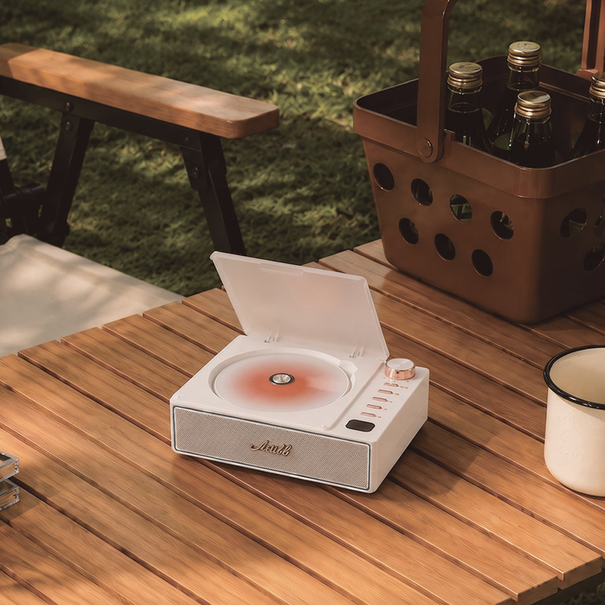 Artikl Portable Bluetooth CD Player in White on an outdoor picnic table, highlighting rechargeable music on the go