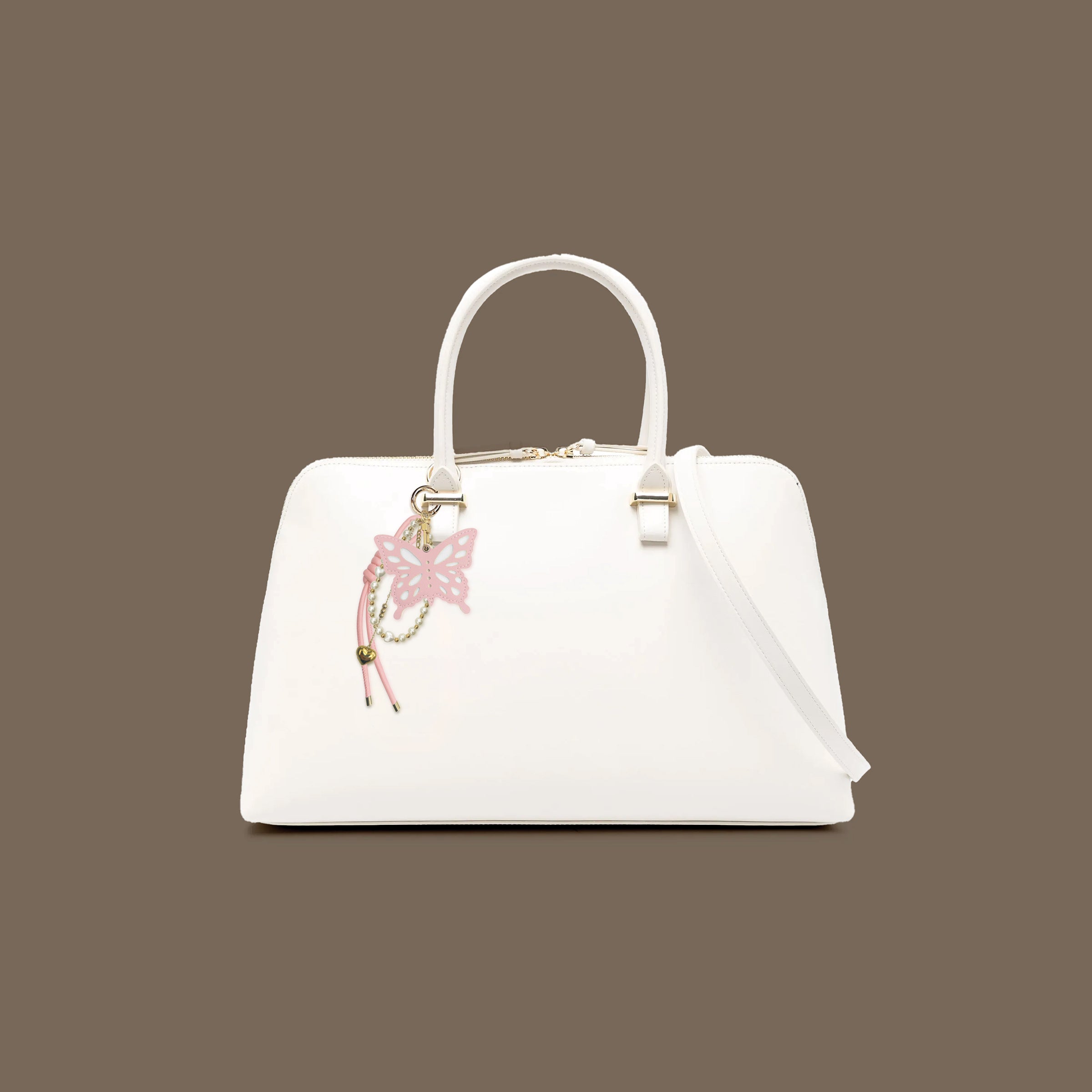 White handbag with a pink butterfly charm on a white background